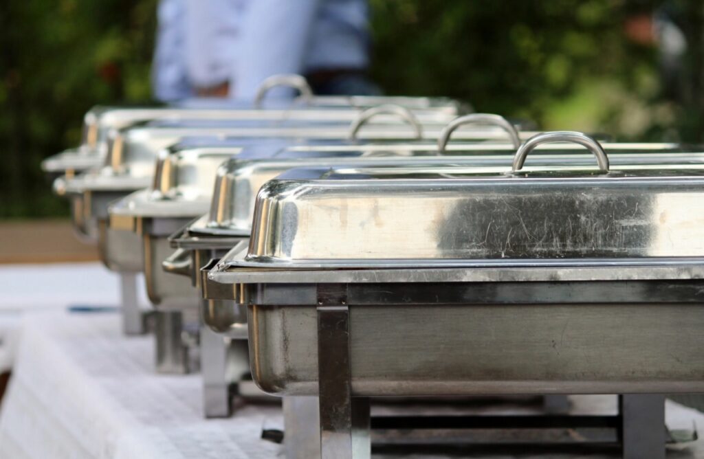 Row of stainless steel chafing dishes keeping catered food hot