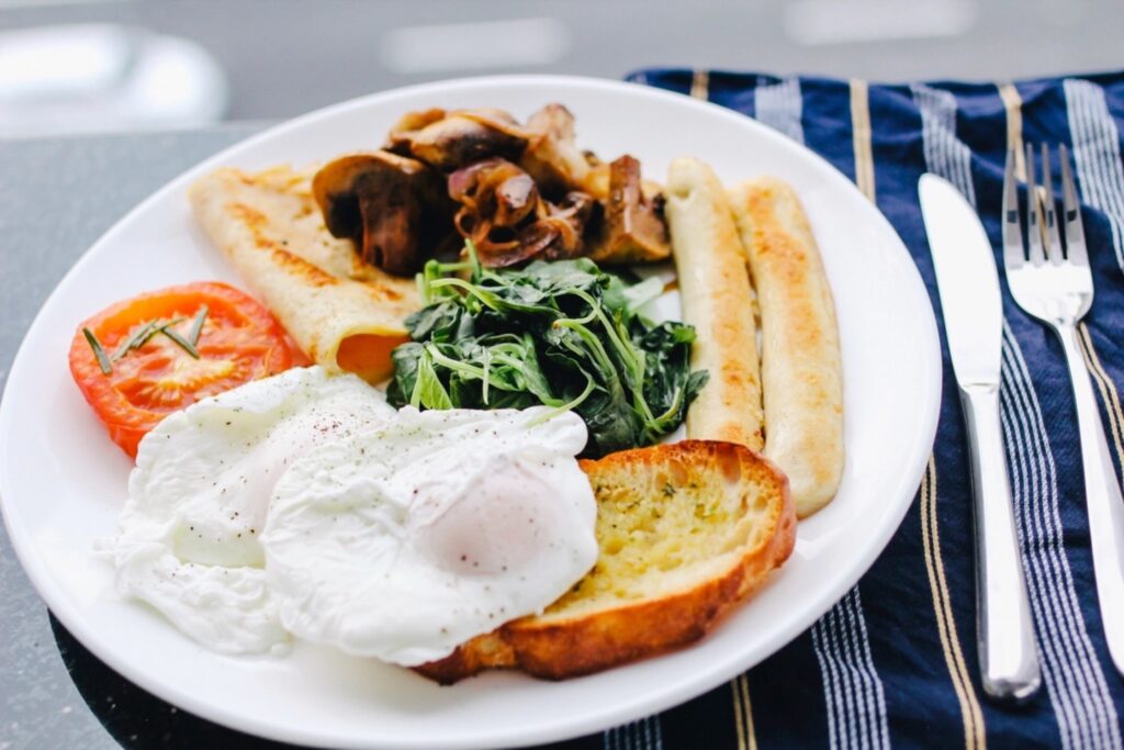 Hot breakfast plate with eggs, sausages, toast, tomatoes and spinach